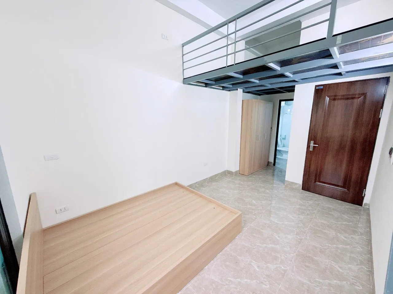 Toàn cảnh phòng ngủ có gác lửng và giường gỗ.