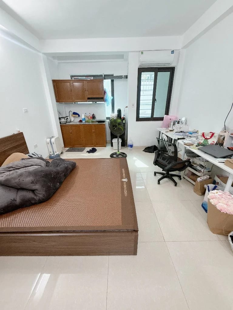 Góc làm việc và giường ngủ lớn bên cạnh tủ bếp gỗ