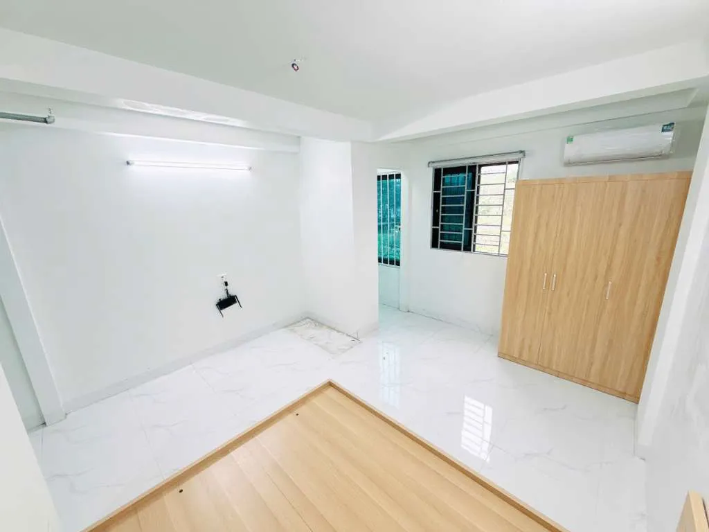 Phòng ngủ có giường gỗ, tủ quần áo và cửa sổ lớn