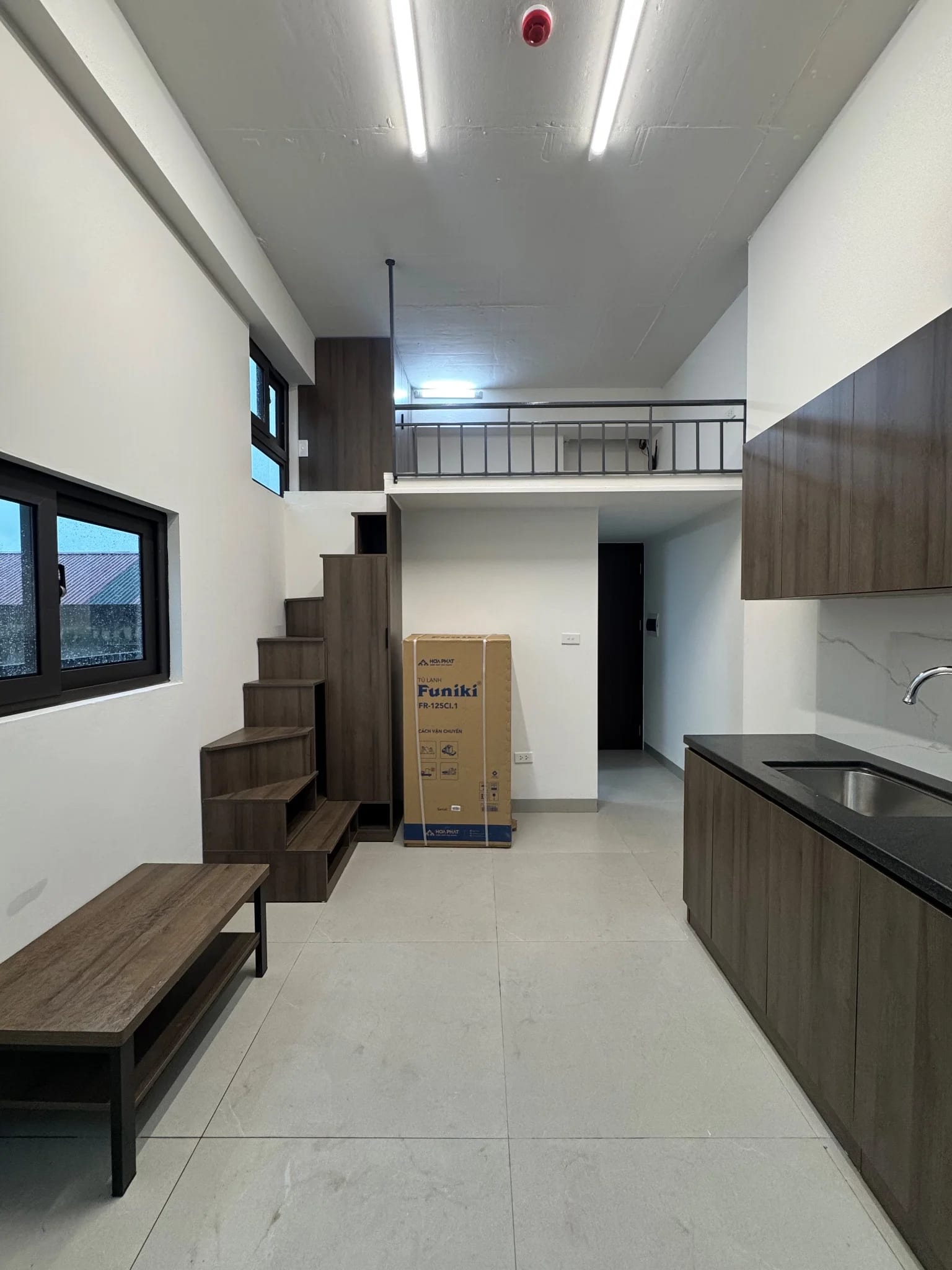 Căn phòng gác lửng có tủ bếp gỗ và cầu thang tiện lợi.